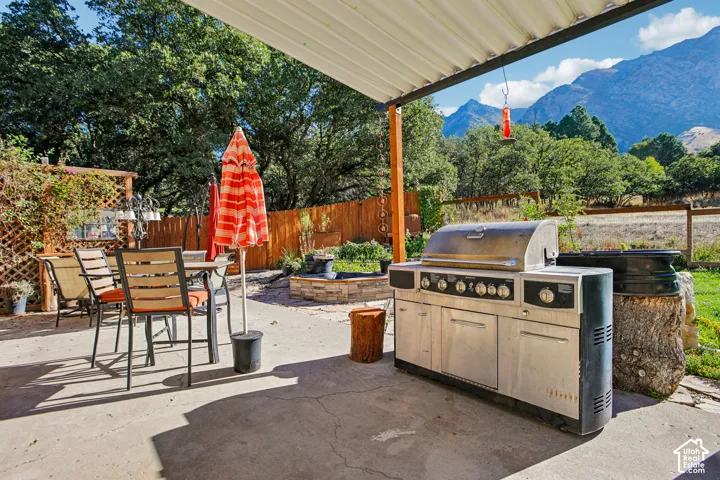 Covered patio with concrete flooring, wood privacy fence, and mountain backdrop