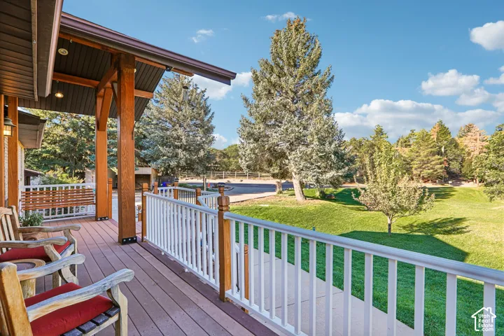 Expansive front porch featuring wood-finish decking, white railings, and exposed timber columns