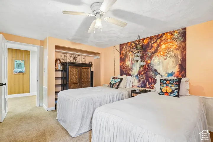 Carpeted flooring, ceiling fan, built-in shelving, paneled accent wall, and wainscoting