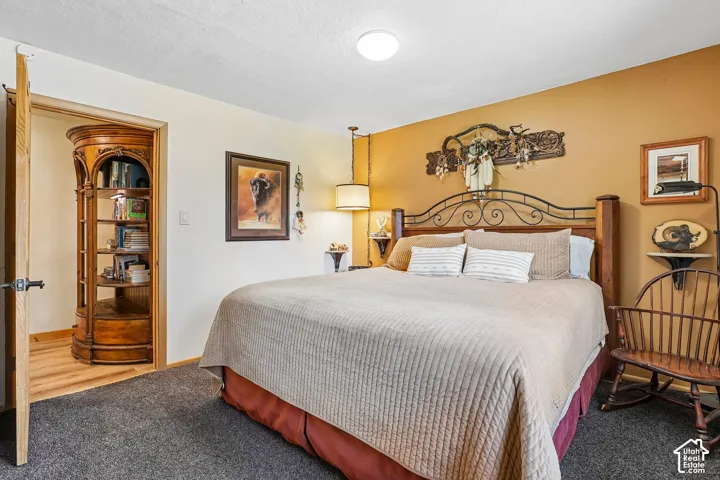 Master bedroom featuring a decorative wrought-iron headboard, recessed ceiling lighting, wood-finish flooring, and a curved wood-frame display cabinet with glass doors