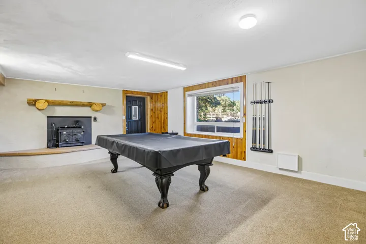 Carpeted floor with built-in wood-burning fireplace, wood mantel, and large window with wood-paneled accents