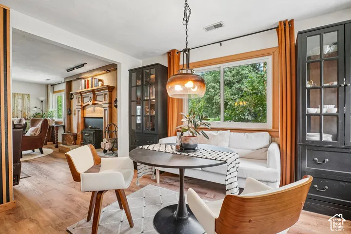 Wood-finish flooring throughout, decorative fireplace mantel, built-in display cabinetry, large window, and overhead pendant lighting