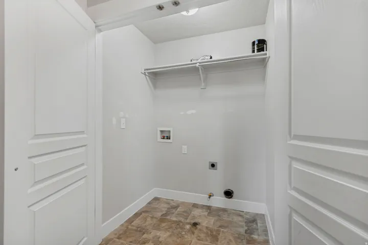 Dedicated laundry area featuring a utility sink connection, dryer vent, and a single storage shelf with hanging rod