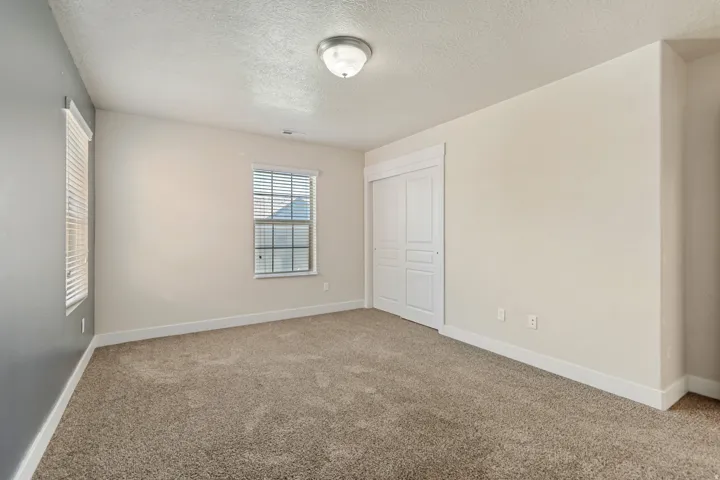 Carpeted flooring, vaulted ceiling, dual pane window with blinds, white trim, and a flush-mount ceiling light