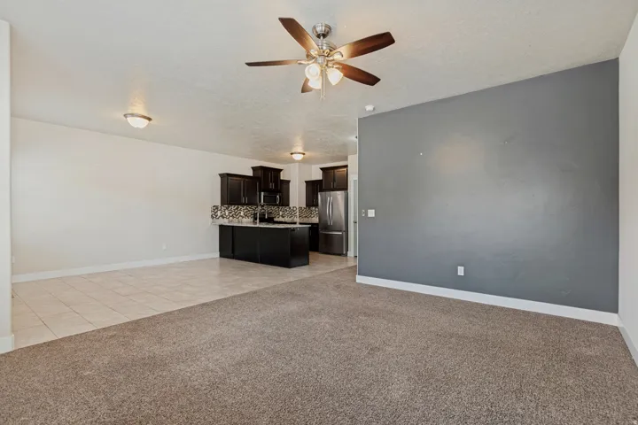 Open-concept living area with a ceiling fan, recessed lighting, and mixed flooring featuring carpet and tile