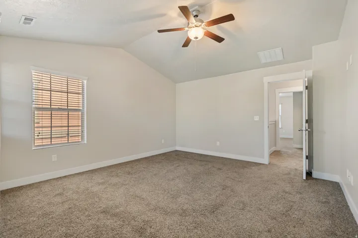 Vaulted ceiling, ceiling fan with integrated lighting, carpeted flooring, window with blinds, and white trim