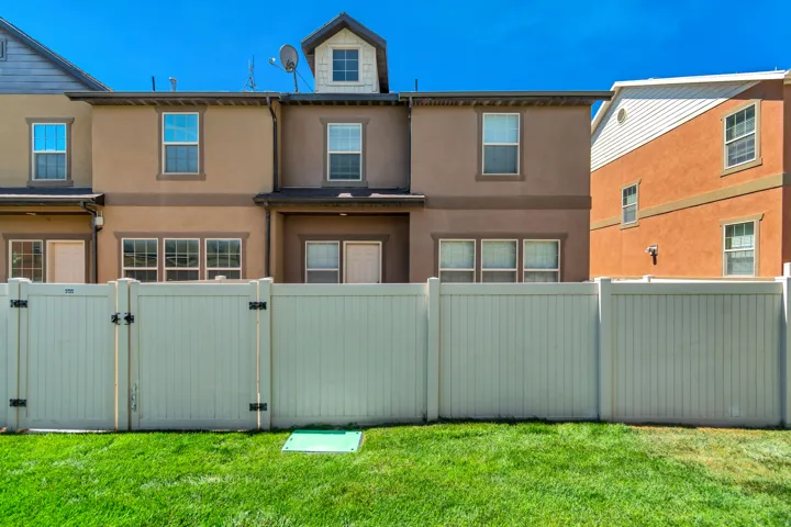 Manicured lawn with a privacy fence and gate, stucco exterior, and multi-pane windows