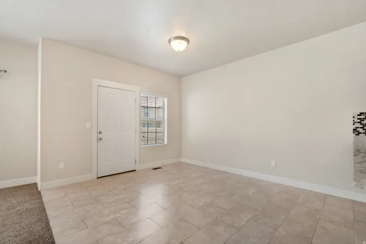 Tiled flooring, neutral wall paint, recessed lighting, white door, and a window with blinds