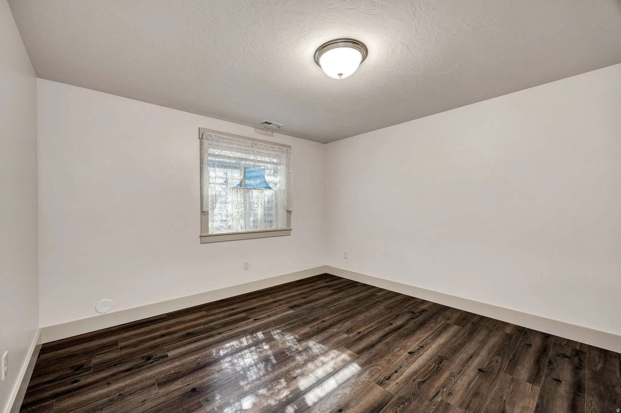 Wood-finish flooring with white walls and a window