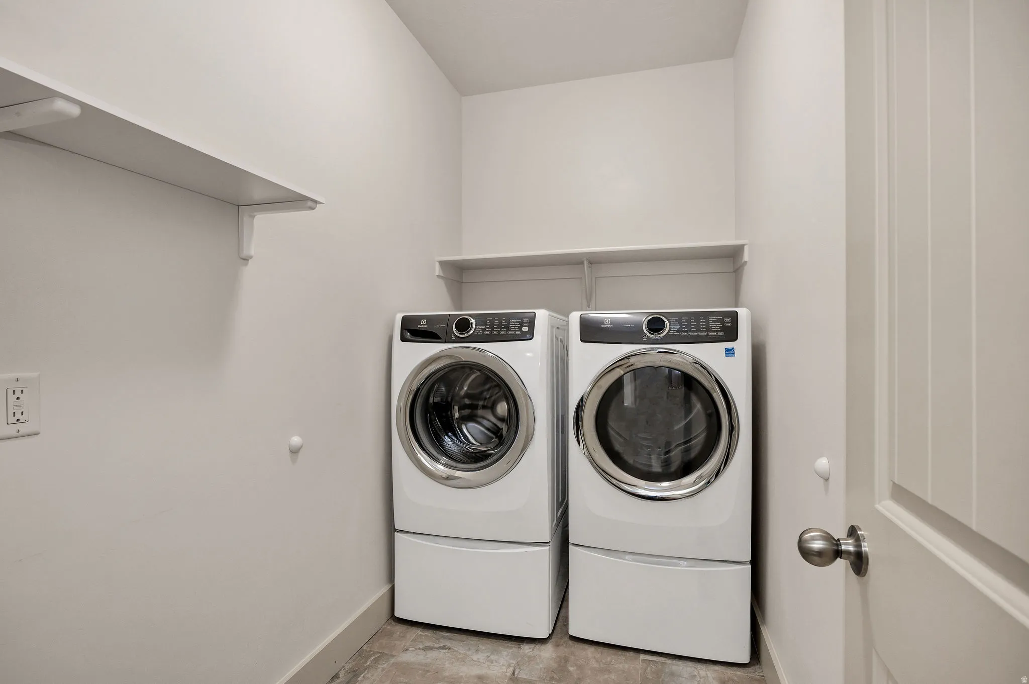 Laundry area featuring a side-by-side washer and dryer, built-in shelving, and wood-finish flooring