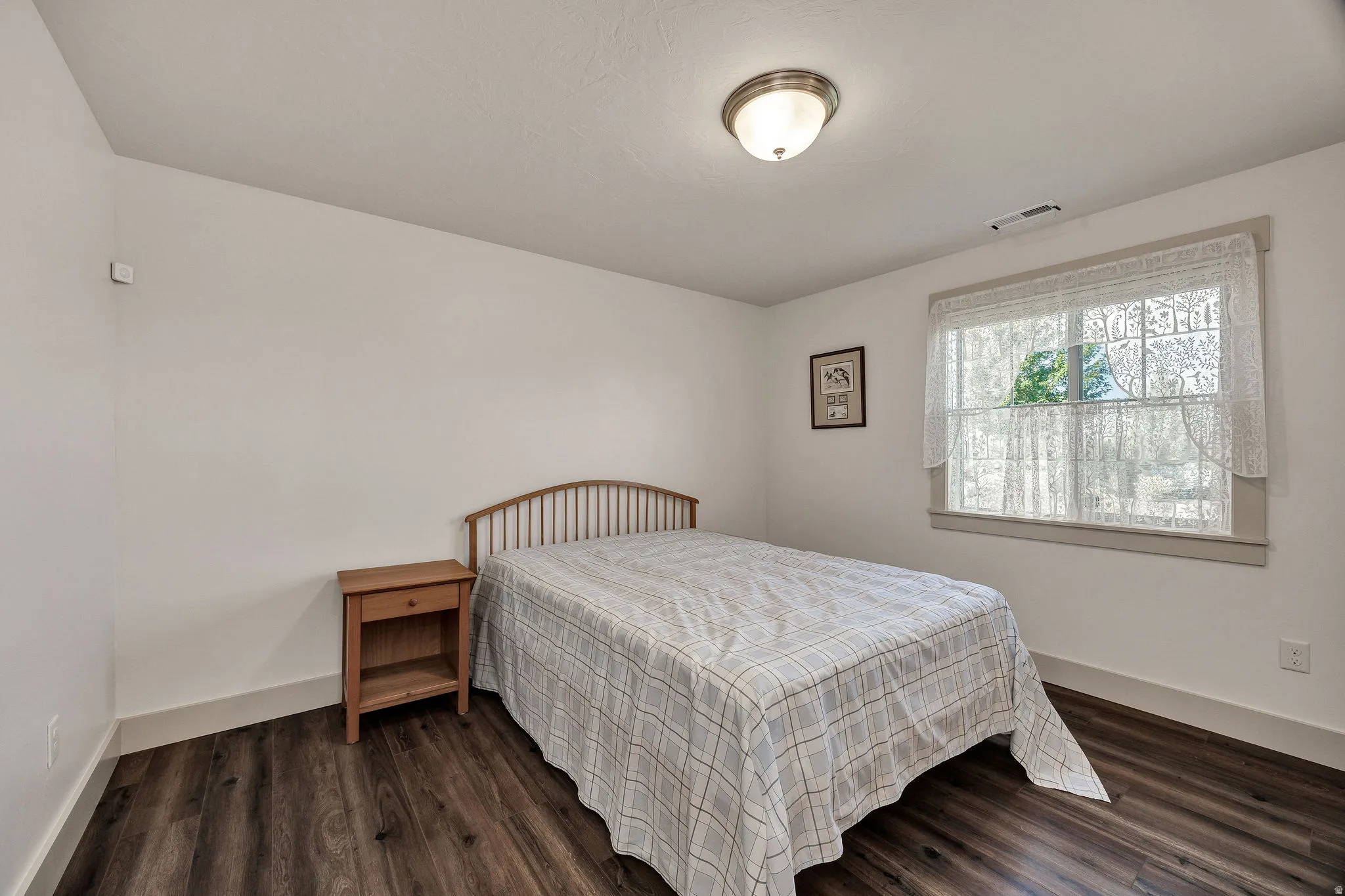 Wood-finish flooring, white walls, and a window with trim detail