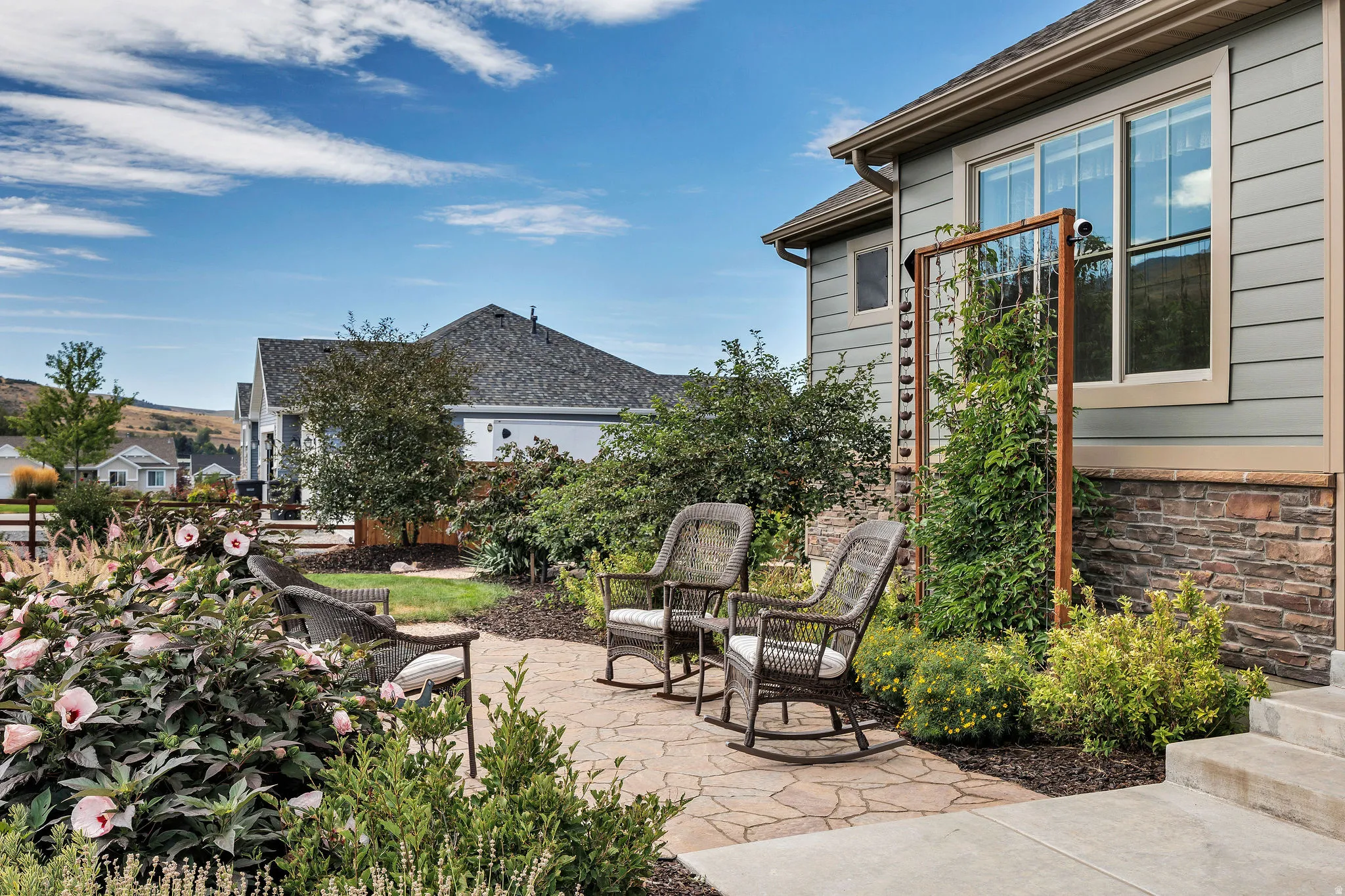 Stone patio featuring a kiwi vine, hybiscus, and established landscaping