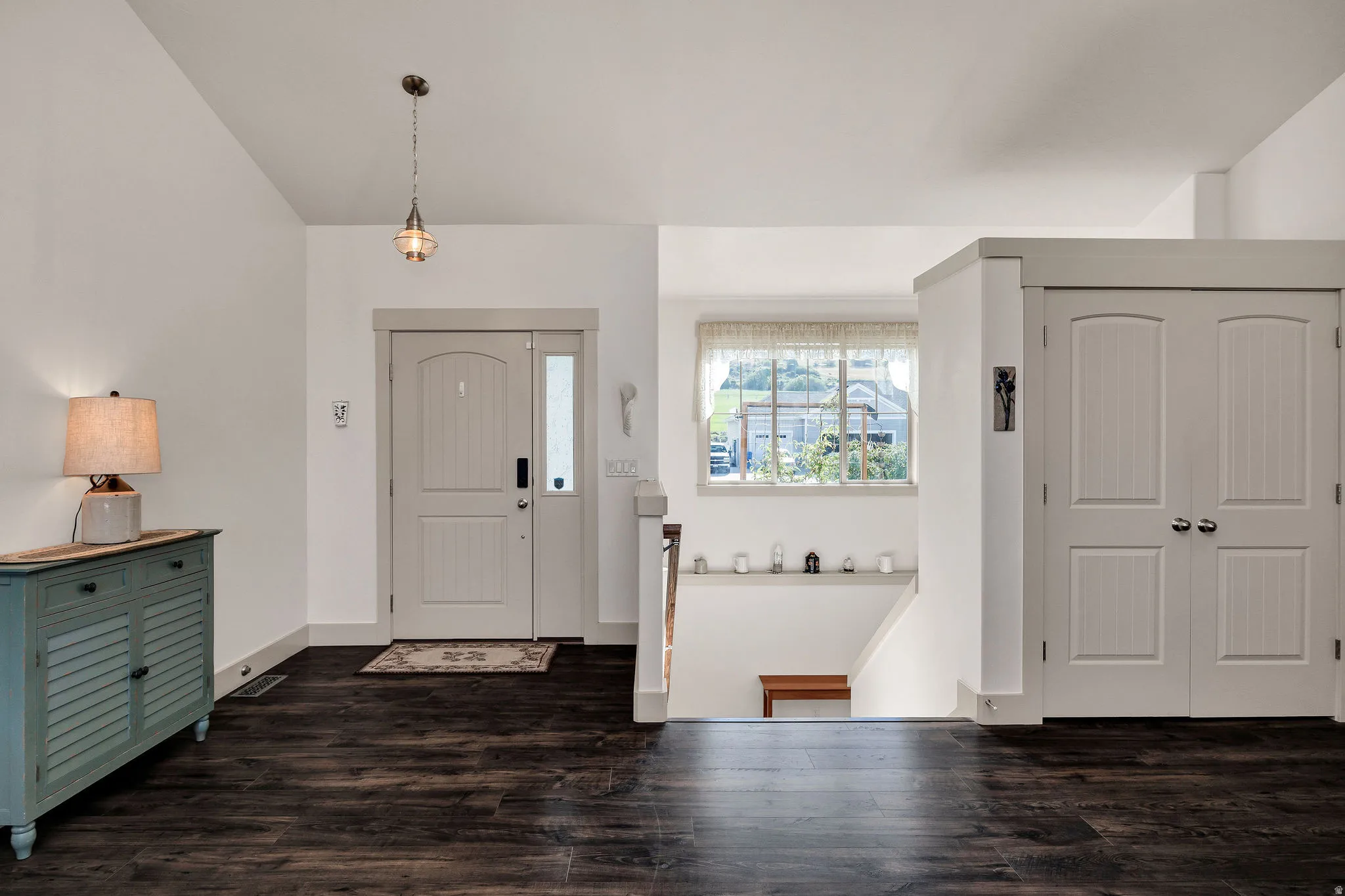 Entryway featuring wood-finish flooring, a light-colored main door with sidelight, and a pendant light fixture
