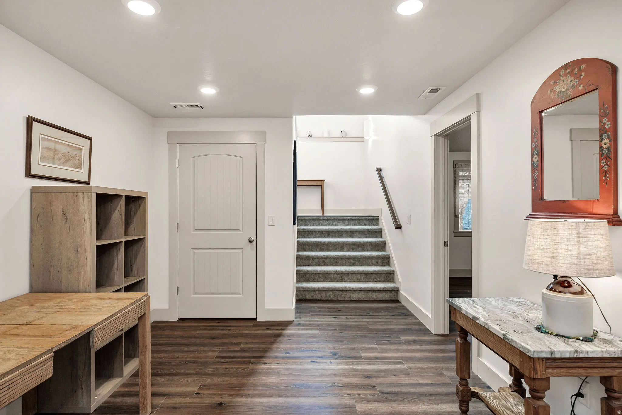 Wood-finish flooring with recessed lighting, white walls, and a carpeted staircase