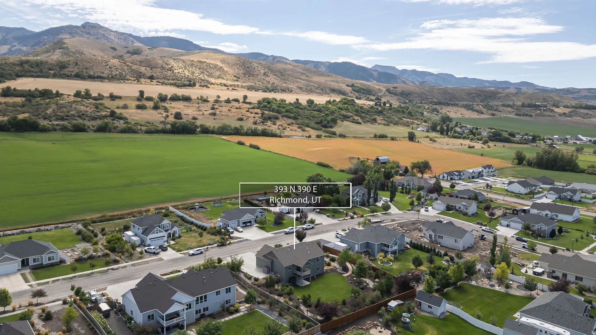 Expansive green fields bordering a residential neighborhood, with distant mountains