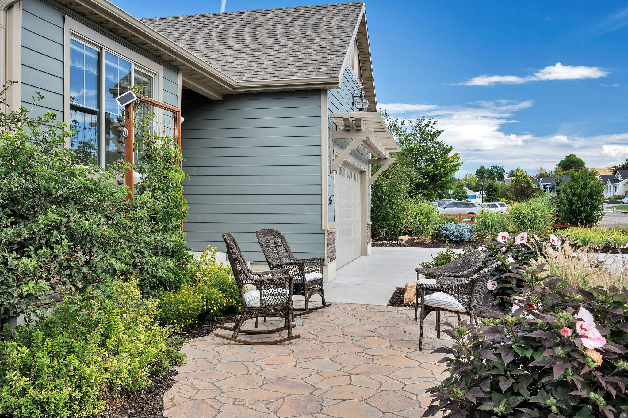 Stone paver patio leading to a concrete driveway