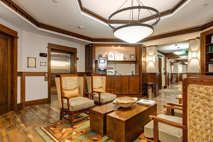Wood-finish flooring, recessed wood paneling, built-in shelving, and a large central light fixture