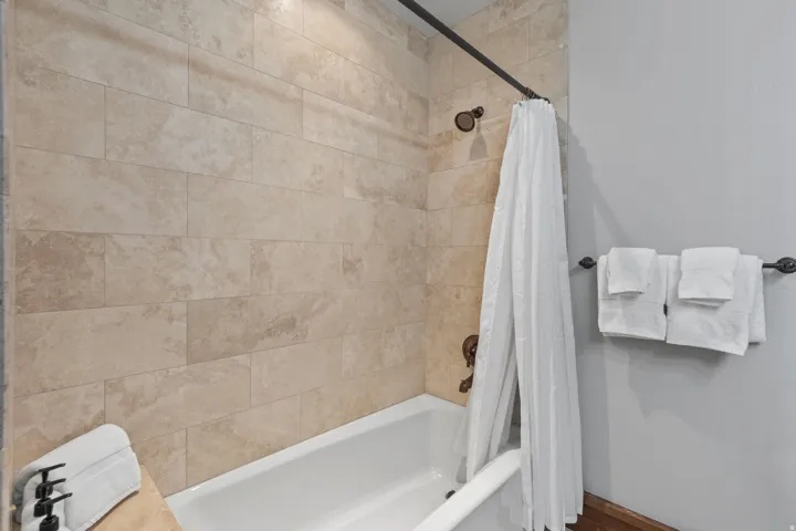 Bathtub with bronze-finish fixtures, tile-surround walls, and a wall-mounted towel bar
