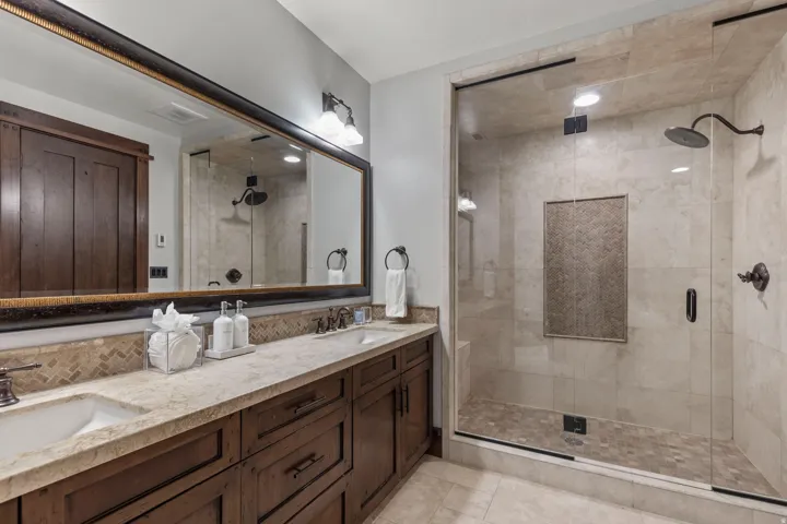 Dual vanity with undermount sinks, wood-finish cabinetry, and stone countertop