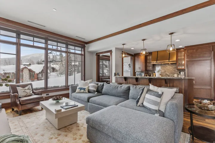 Expansive window wall with dark wood trim, open concept living area, kitchen with dark wood cabinetry, solid surface countertops, and pendant lighting