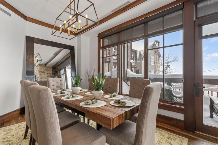 Dining area featuring wood-finish flooring, a large wood-framed mirror, and an open-frame chandelier