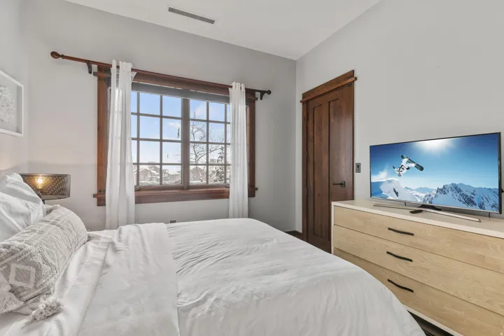 Gridded window with wood-finish trim, solid wood-finish door, and light wood-finish dresser with dark hardware