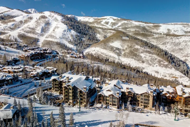 Mountain resort property with multiple multi-story buildings, snow-covered roofs, and visible ski slopes