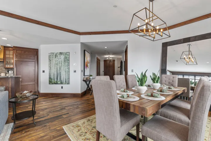 Wood-finish flooring, exposed wood beams, bronze chandelier, built-in refrigerator, and wood cabinetry
