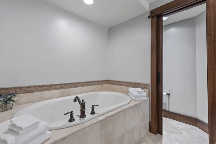 Built-in soaking tub with oil-rubbed bronze fixtures, set in a tiled surround with a decorative accent border