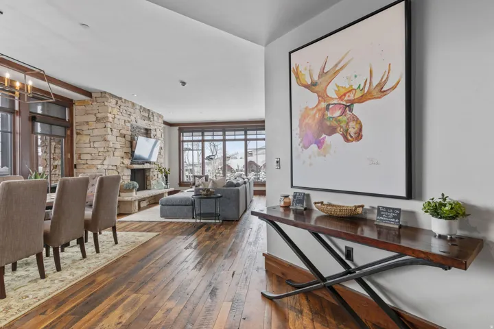 Hardwood flooring, stone fireplace, large windows, recessed lighting, and a built-in console table