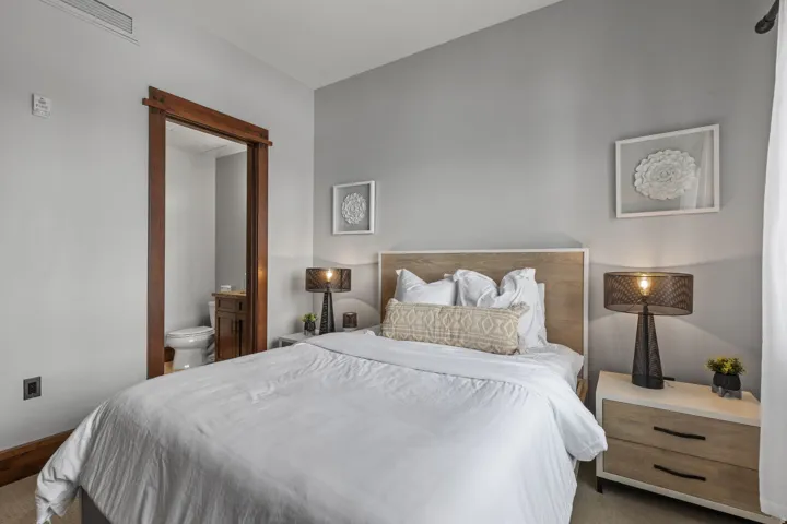 Hardwood door frame, light wood-finish headboard, high ceilings, light wood-finish nightstand with black hardware, and light wood-finish flooring