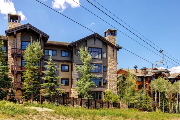 Multi-story building featuring stone and siding exterior, multiple balconies, and prominent chimneys