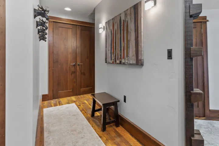 Rich wood-finish double doors, wood-finish flooring, and a textured accent wall