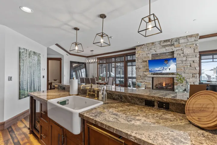 Kitchen island with a farmhouse sink, stone countertops, and wood-finish cabinetry