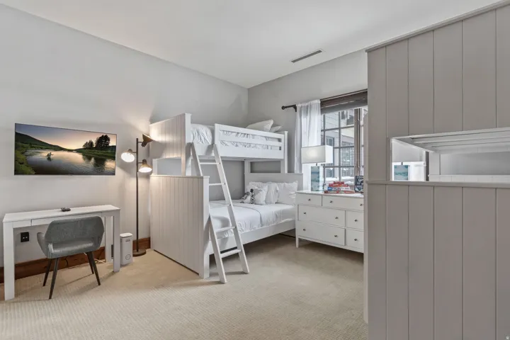 Built-in bunk beds with integrated ladder and storage, soft carpeting, and a window with architectural detailing