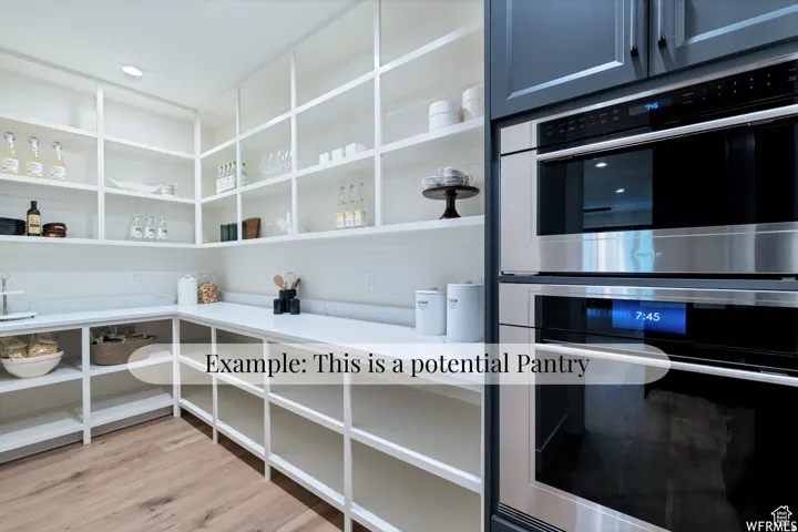 Extensive built-in shelving, ample counter space, wood-finish flooring, and integrated stainless steel double ovens