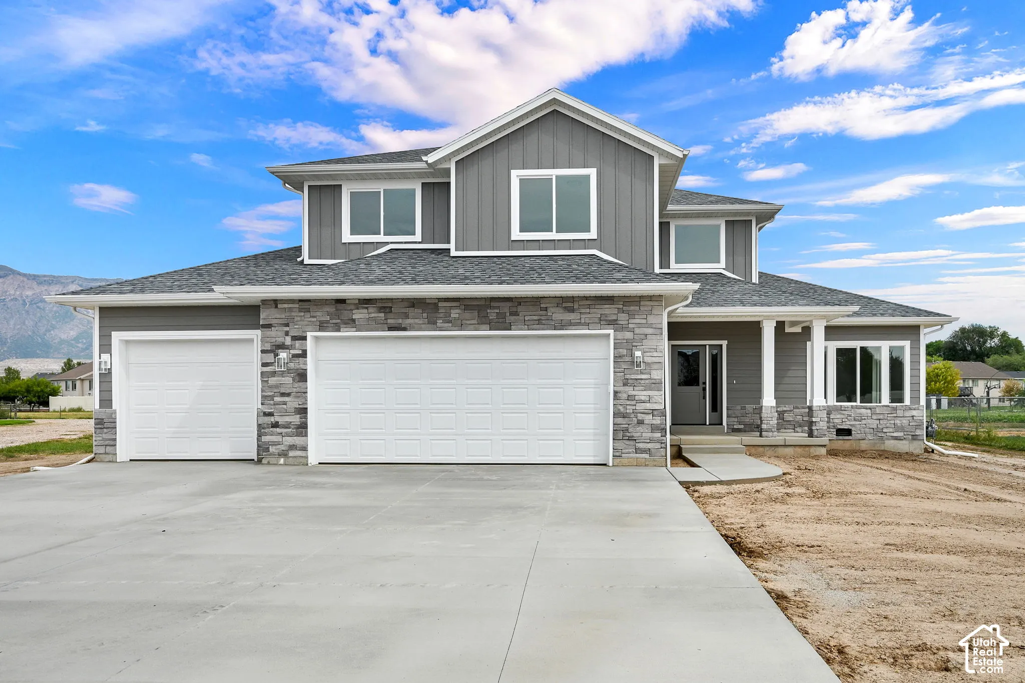 Modern exterior featuring gray siding, stone accents, multiple large windows, and an attached three-car garage