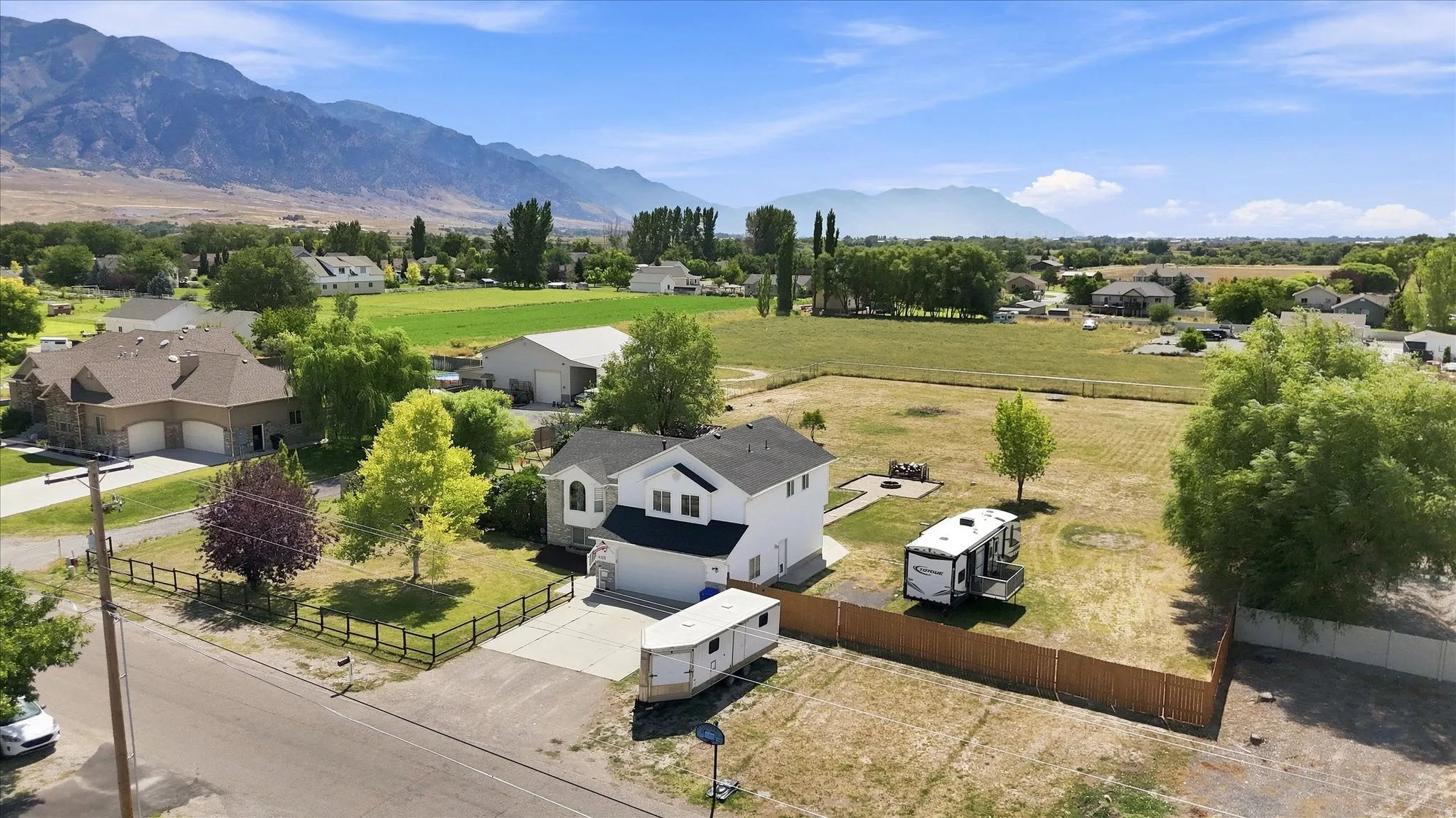 White exterior with black roof, attached garage, concrete driveway, and fenced yard