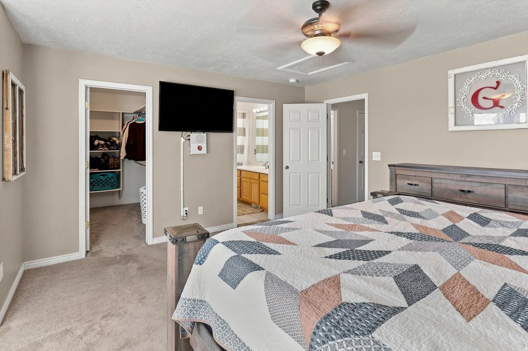 Neutral wall paint, ceiling fan with integrated lighting, built-in closet shelving, and carpeting throughout