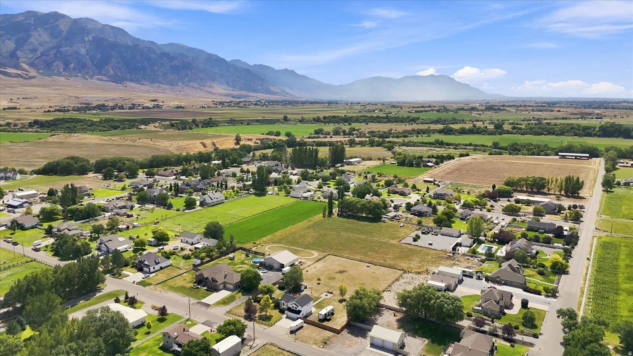 Expansive community with scattered residential properties, surrounded by open fields and distant mountains