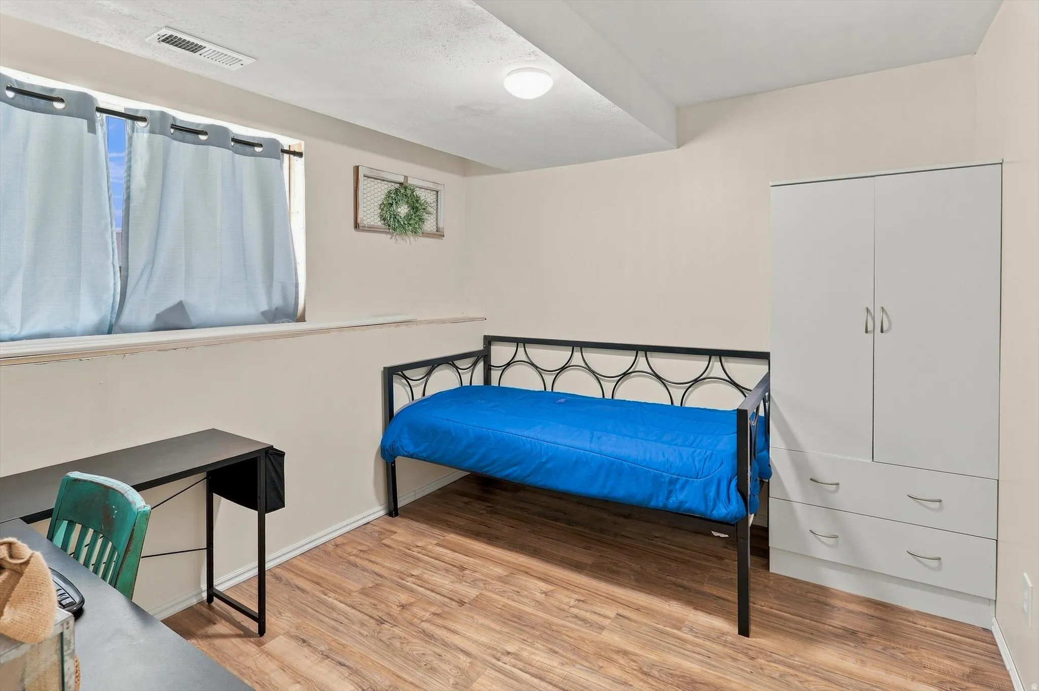 Wood-finish flooring with a low-profile window, a built-in wardrobe, and ceiling-mounted lighting