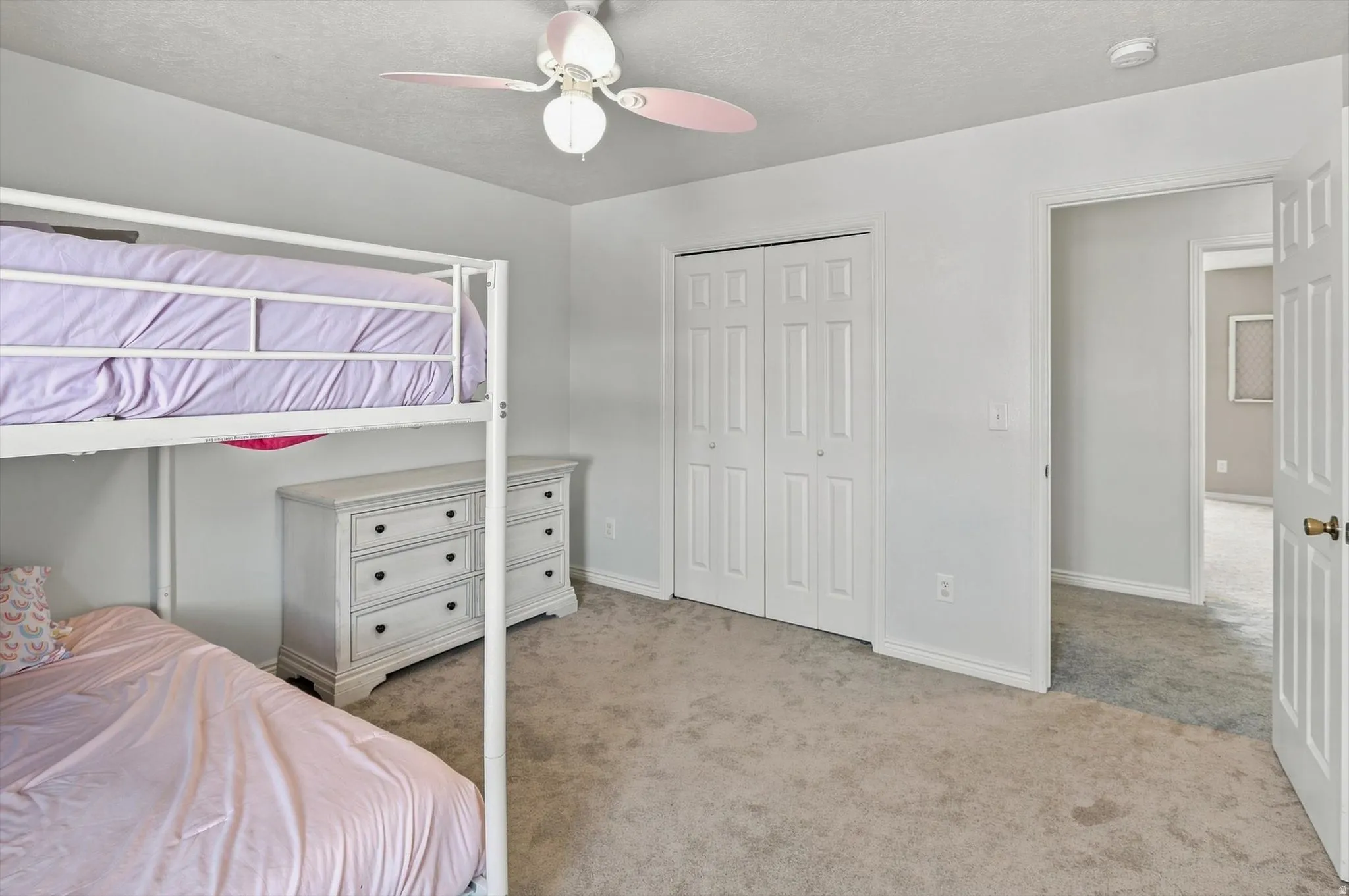 Neutral wall paint, carpet flooring, a ceiling fan with integrated lighting, and a bi-fold closet
