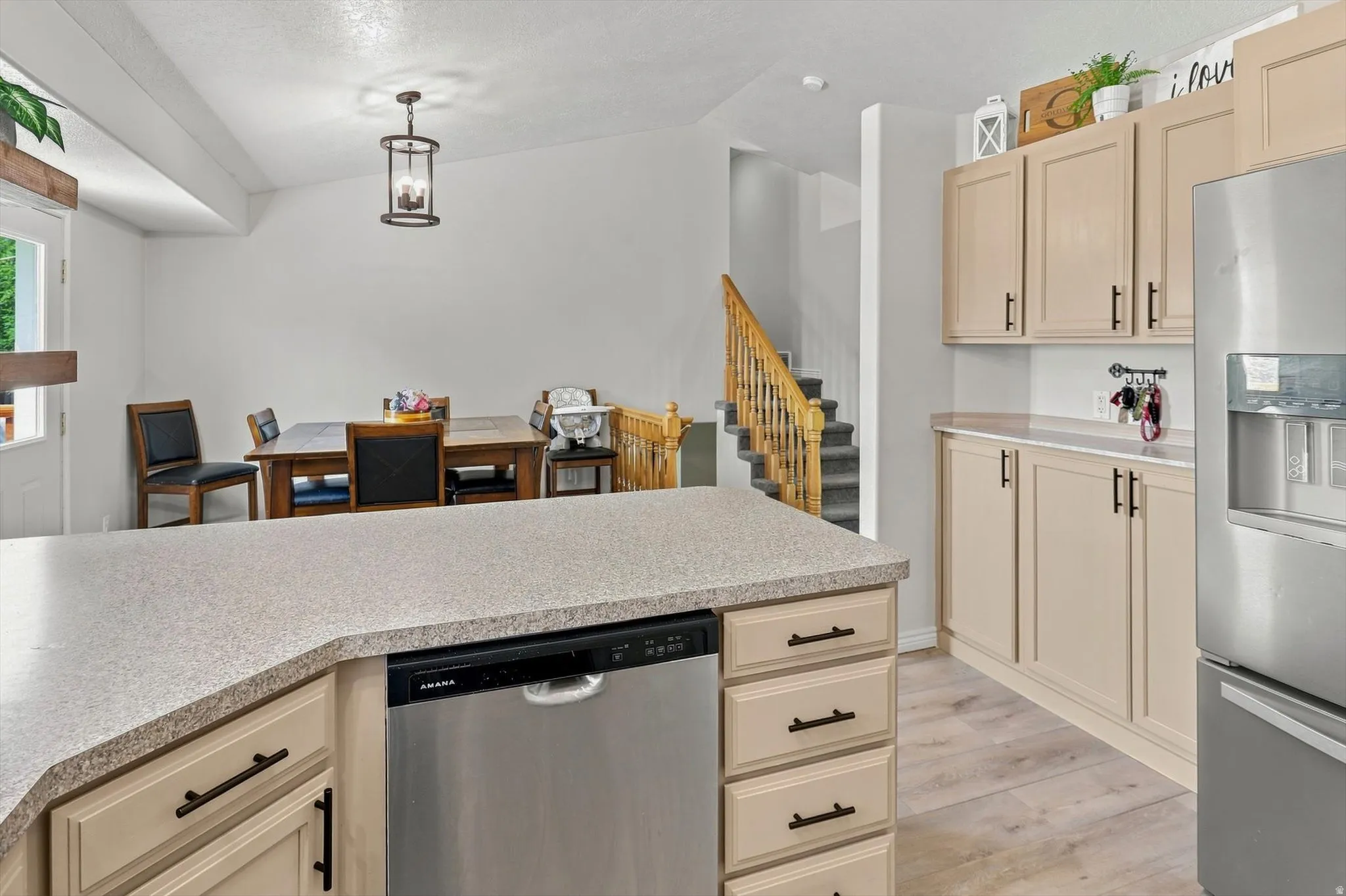 Kitchen island with a built-in dishwasher, neutral cabinetry with dark hardware, solid surface countertops, and light wood-finish flooring