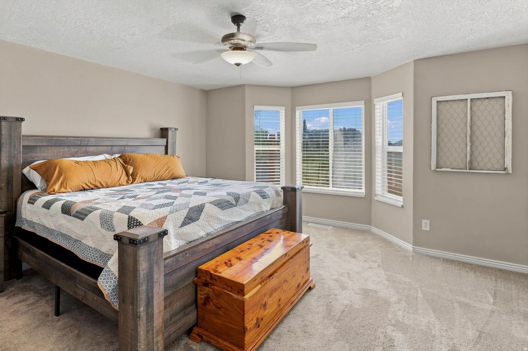 Expansive room featuring carpeted flooring, a ceiling fan with integrated lighting, and multiple windows with blinds