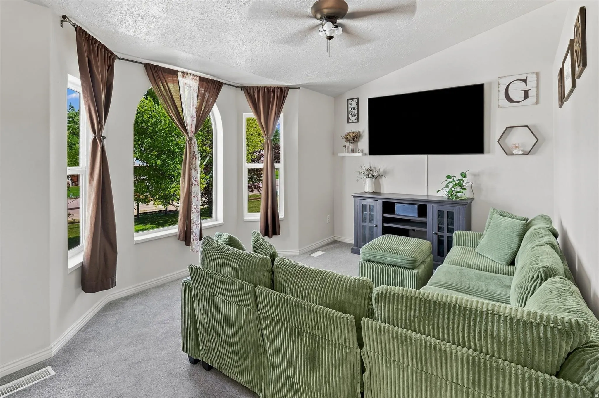 Living area with vaulted ceilings, recessed wall for entertainment setup, and multiple arched windows