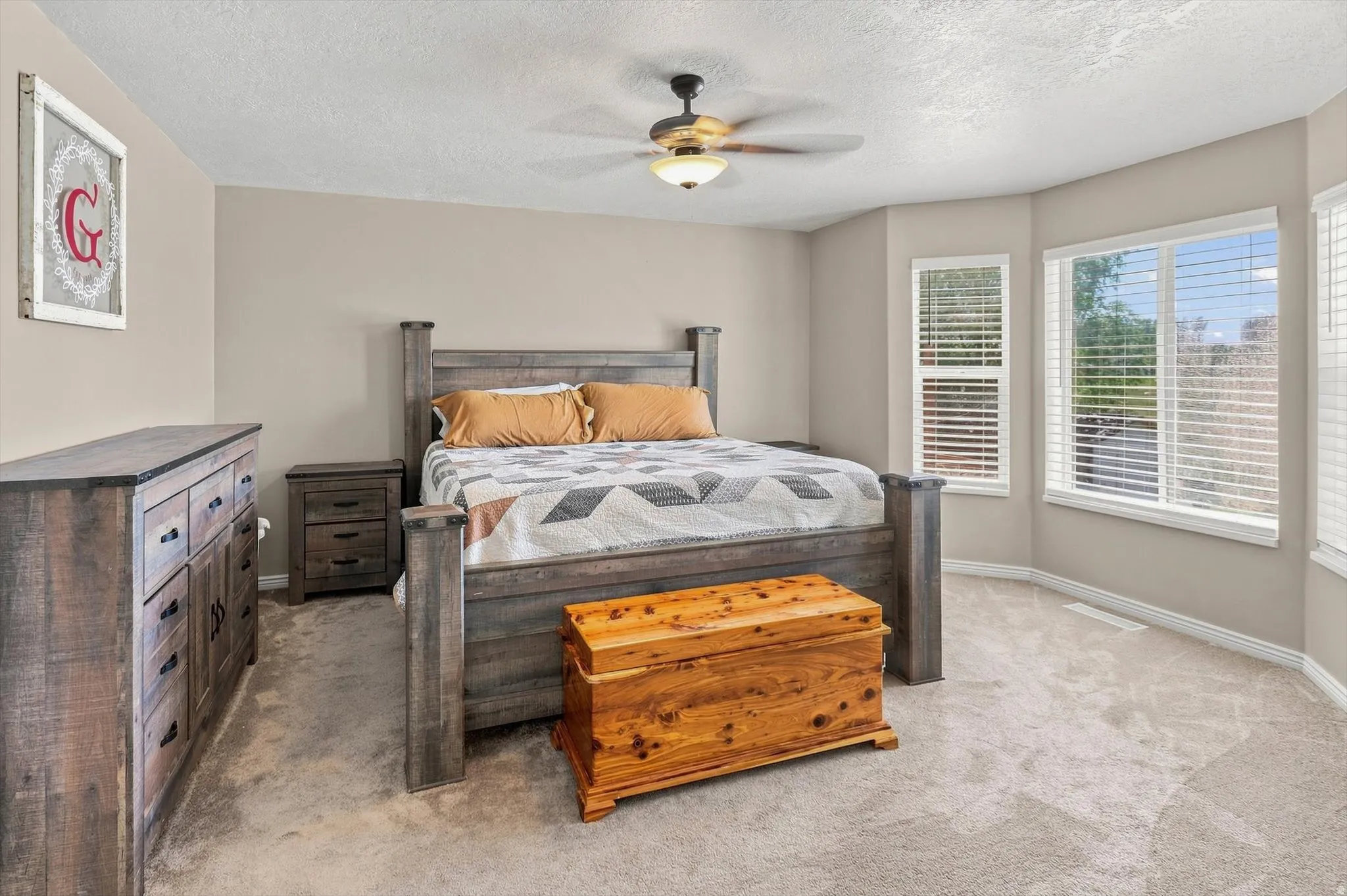 Bay window with multiple panes, ceiling fan with integrated lighting, and neutral wall tones