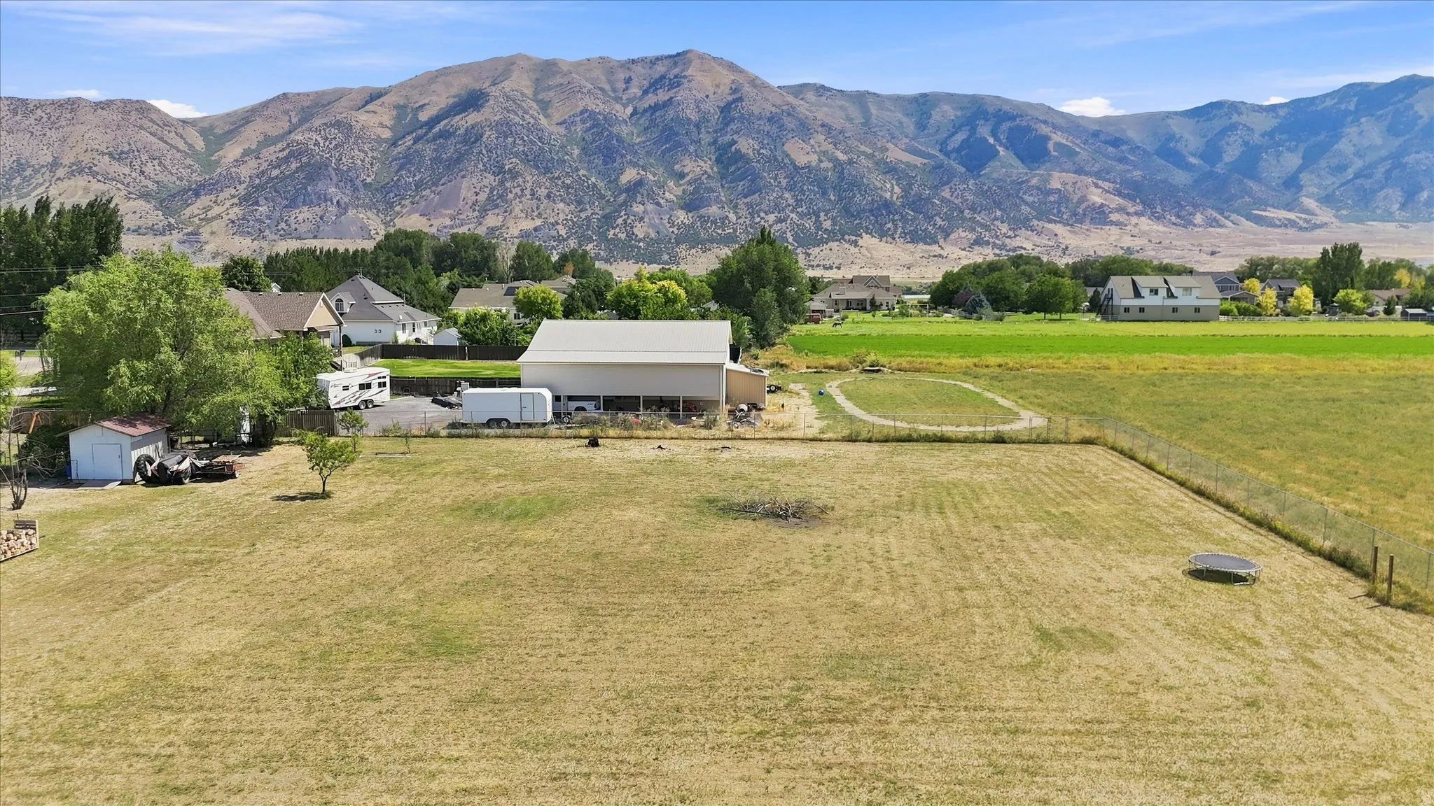 Expansive lot with a large outbuilding, a secondary storage shed, and mature trees