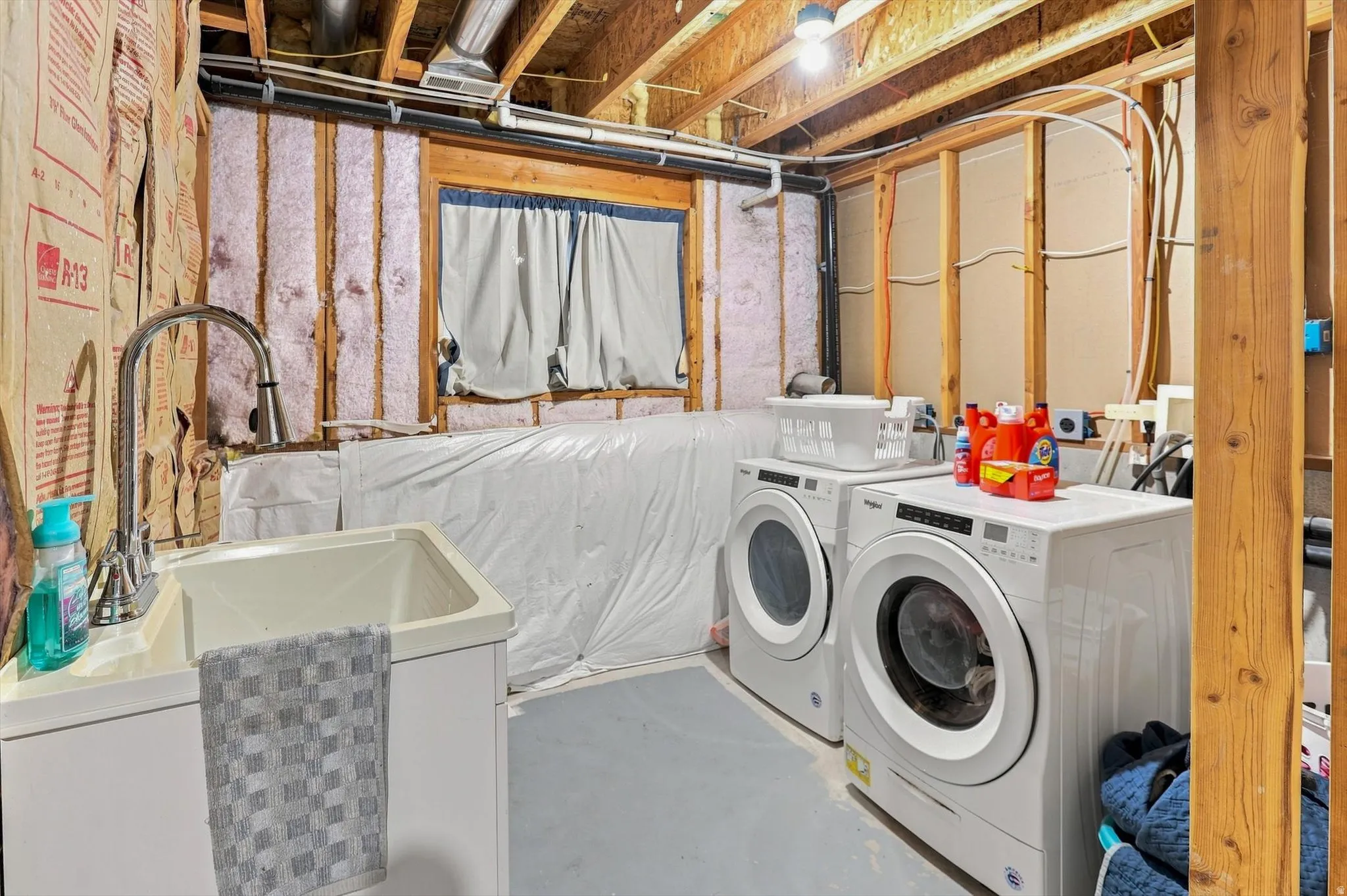 Utility sink with gooseneck faucet, exposed ceiling joists, and visible insulation