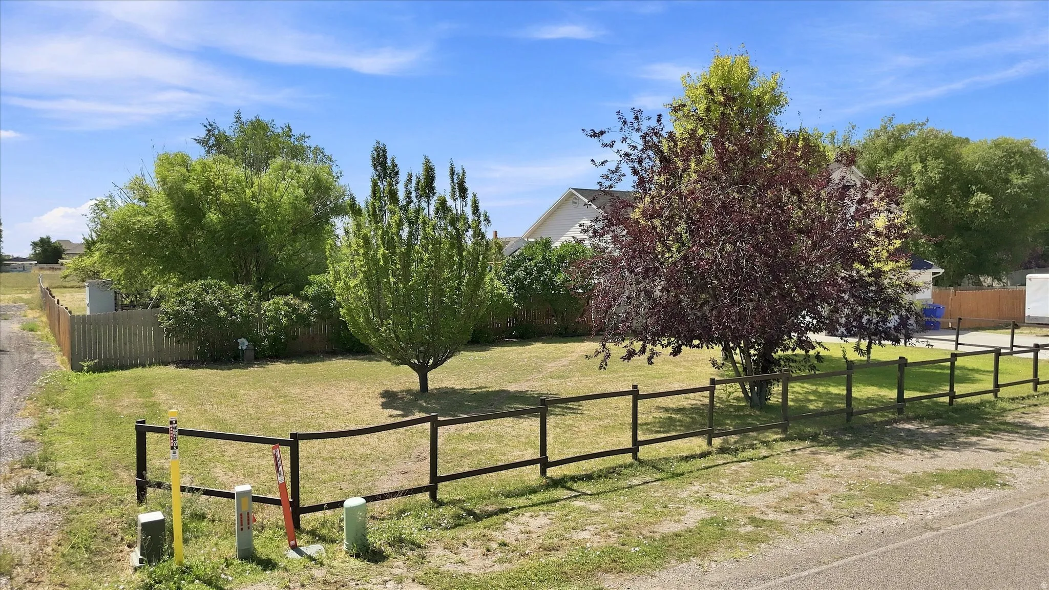 Expansive lot with established trees and a partial wood fence