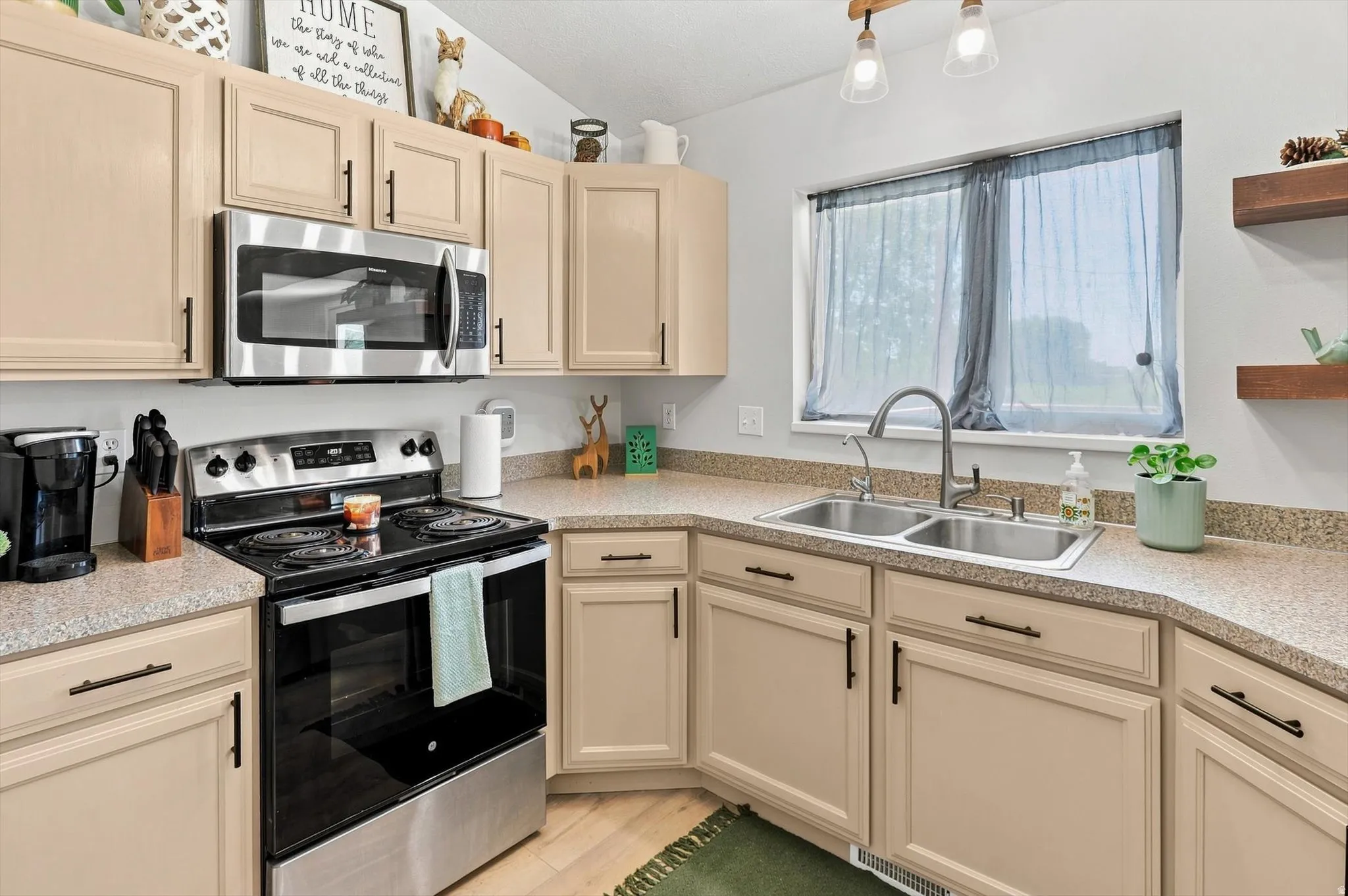 Kitchen featuring light-toned cabinetry, stainless steel appliances, a double basin sink with a gooseneck faucet, and speckled countertops